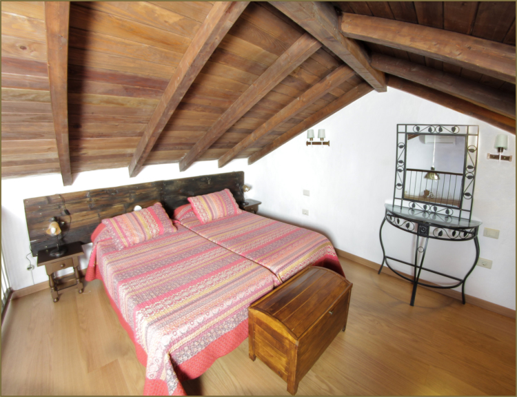 Vivienda 1 – Dormitorio abuhardillado con techo de madera