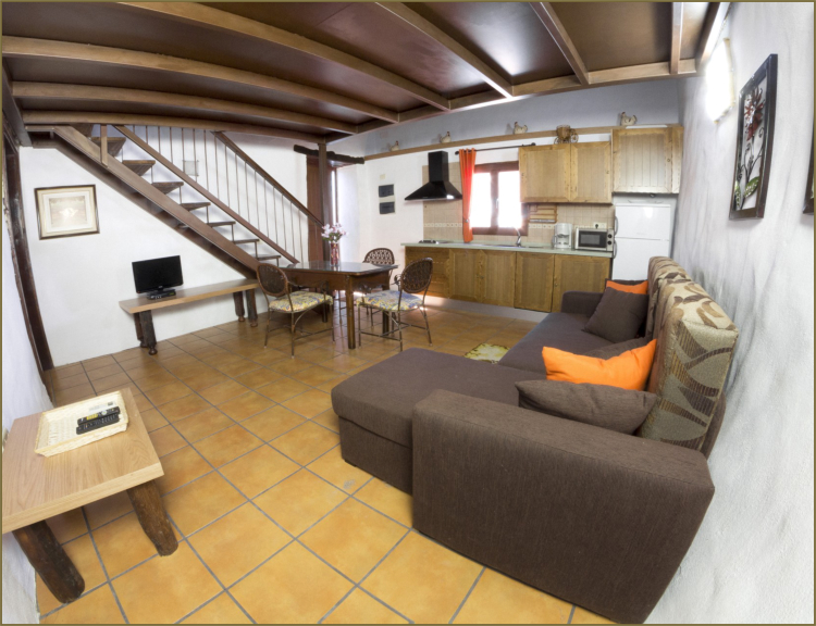 Vivienda 1 – Salón con sofá y vigas de madera